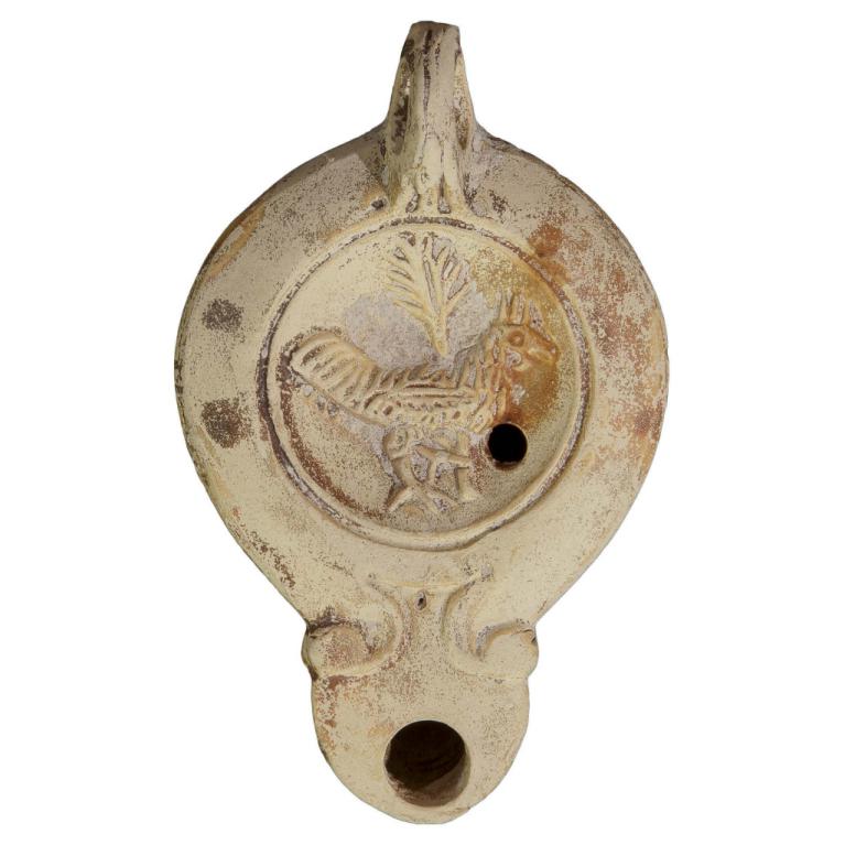 Lampe à huile en terre cuite à bec en ogive et à doubles volutes, Coq de profil droit qui enserre avec sa patte gauche une palme verticale (symbole de la victoire) Signature LMADIEC 20121125 030 Lampe à huile en terre cuite à bec en ogive et à doubles volutes, Coq de profil droit qui enserre avec sa patte gauche une palme verticale (symbole de la victoire) Signature LMADIEC 20121125 030