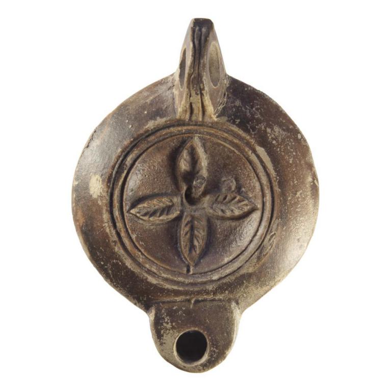 Rosace de quatre feuilles dentelées disposées en croix. Anse forée à deux sillons. Bandeau de type Loeschcke VII a. Bec Bus. 4a. Base circulaire à une incision. IIe s. ap. J.-C. Voir Bussière 16, n° 2588, collection Rivel n° 187. Signature, LMADI D. 101 x 72 x 28 mm Acquisition SVV Fraysse & Associés, Paris. N° 20160608 041 Rosace de quatre feuilles dentelées disposées en croix. Anse forée à deux sillons. Bandeau de type Loeschcke VII a. Bec Bus. 4a. Base circulaire à une incision. IIe s. ap. J.-C. Voir Bussière 16, n° 2588, collection Rivel n° 187. Signature, LMADI D. 101 x 72 x 28 mm Acquisition SVV Fraysse & Associés, Paris. N° 20160608 041
